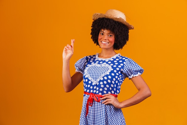 Brazilian afro woman wearing typical clothes for the Festa Junina on yellow