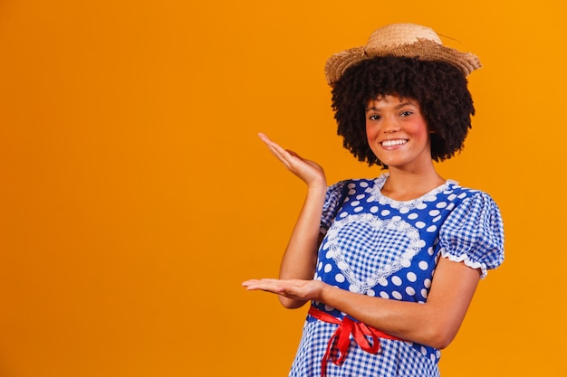 Brazilian afro woman wearing typical clothes for the Festa Junina on yellow