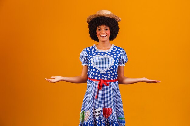 Foto donna afro brasiliana che indossa abiti tipici per la festa junina su giallo