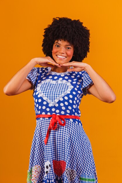 Brazilian afro woman wearing typical clothes for the Festa Junina on yellow
