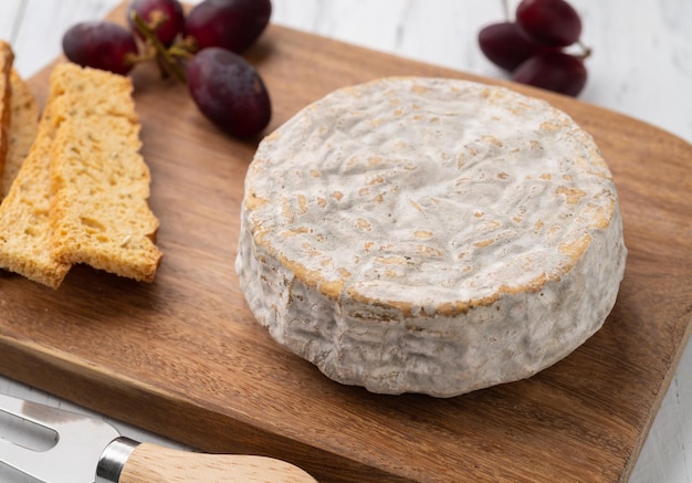 Brazilian artisan Bofete blue cheese with bread nuts and fruits over wooden table