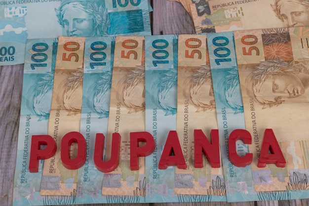 Brazilian bank notes called real in notes of 100 and 50 with red writing in Portuguese Poupanca