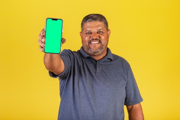 Brazilian black man adult pointing at cellphone screen negative space for advertisement