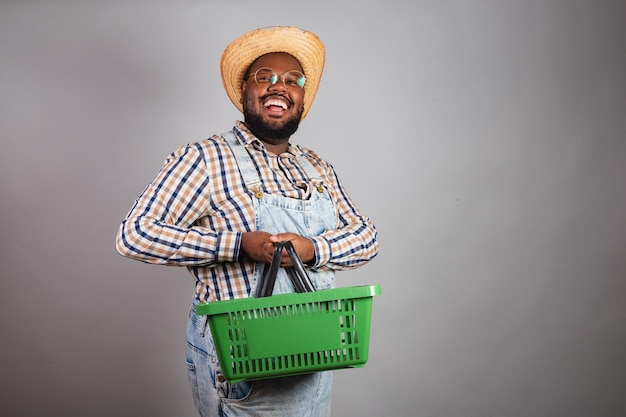 Brazilian black man wearing country clothes from festa junina festa de sao joao arraia holding market basket shopping promotions