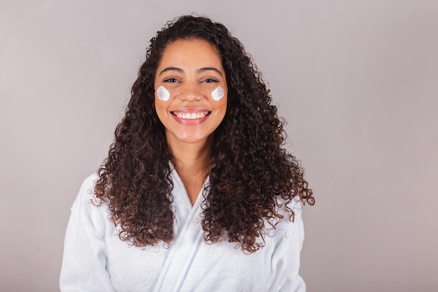 Brazilian black woman wearing bathrobe and towel face cream spa beauty center skin care