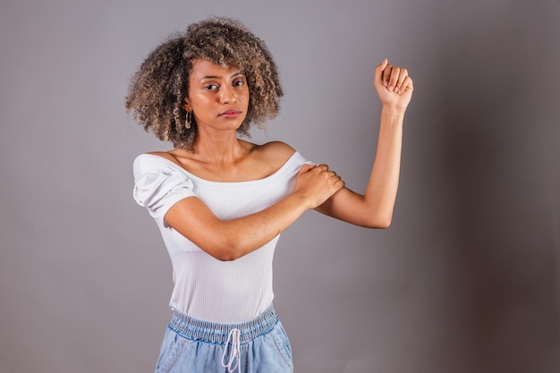 Бразильская чернокожая женщина с высоко сжатым кулаком в феминистской позе борется за расширение прав и возможностей женщин