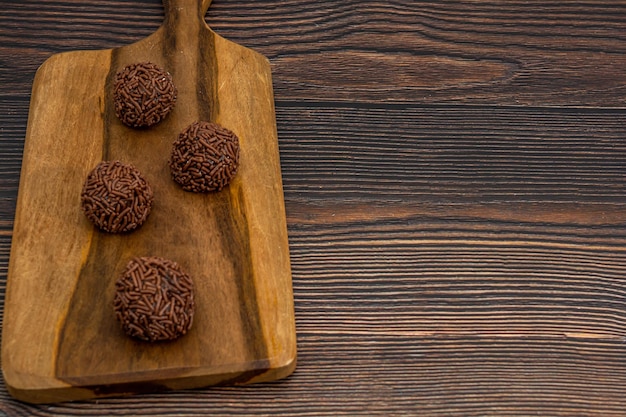 브라질 브리가데이로(Brigadeiro) 전통 맛있는 초콜릿 디저트 파티 간식은 나무 탁자 위에 달콤한 뿌리는 배경입니다.