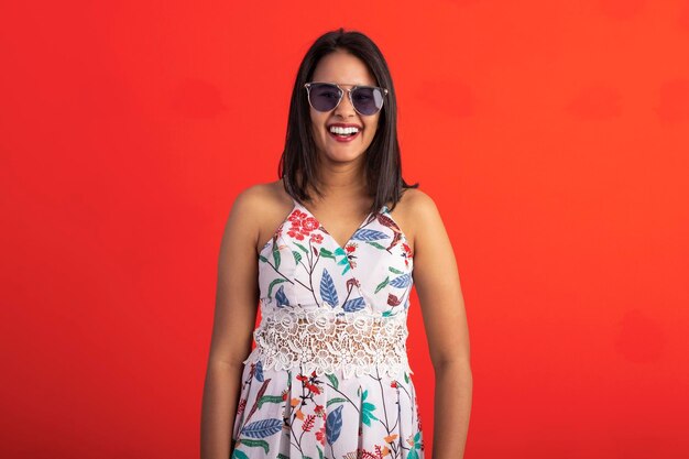 Brazilian brunette woman in flower print dress in studio wearing eyeglasses and sunglasses