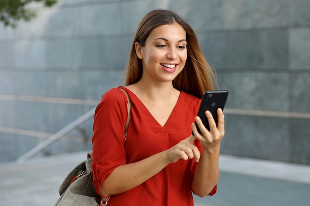 Brazilian caucasian business woman using shopping online app on smart phone in the street