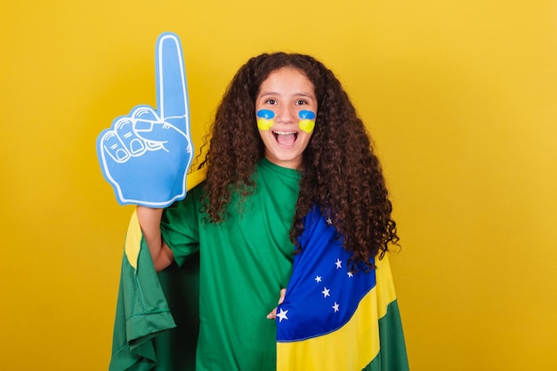 Foto ragazza brasiliana del tifoso caucasica con la mano di schiuma che urla all'obiettivo e fa festa