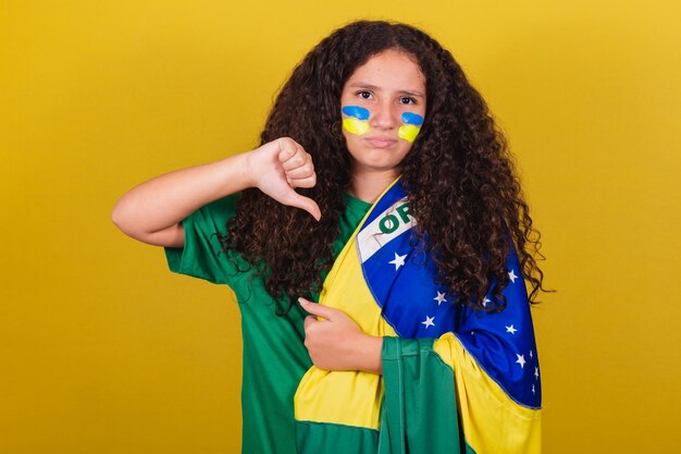 Бразильская кавказская девушка-футболист неодобрительно опускает пальцы вниз, грустно, несчастна