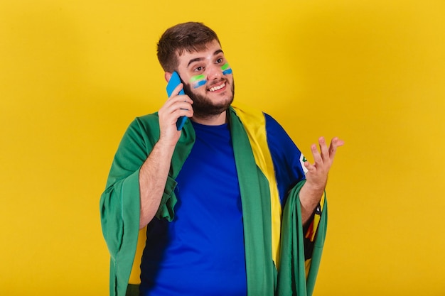 Brazilian caucasian man soccer fan from brazil chatting voice\
call on his cellphone selfie smartphone