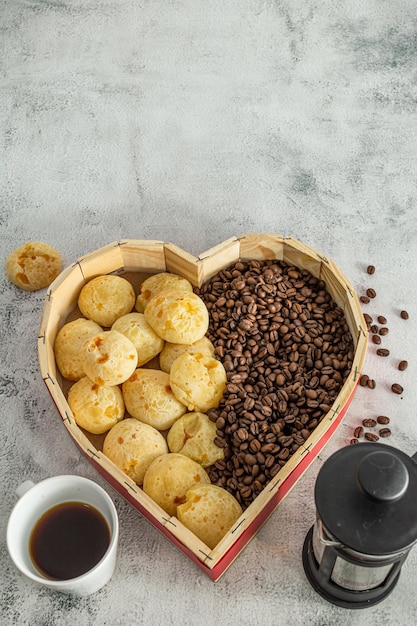 Brazilian cheese bread or cheese bun in a heart shaped format basket with coffee beans