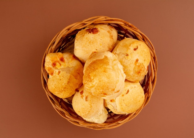 Brazilian cheese bread isolated inside a wooden basket in brown background in aerial top view