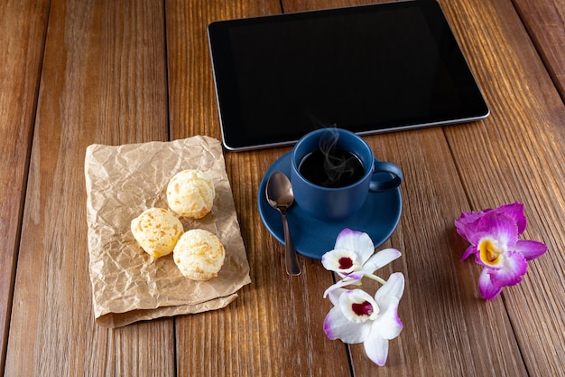 태블릿 커피 컵 구리 숟가락과 꽃 옆에 브라질 치즈 빵