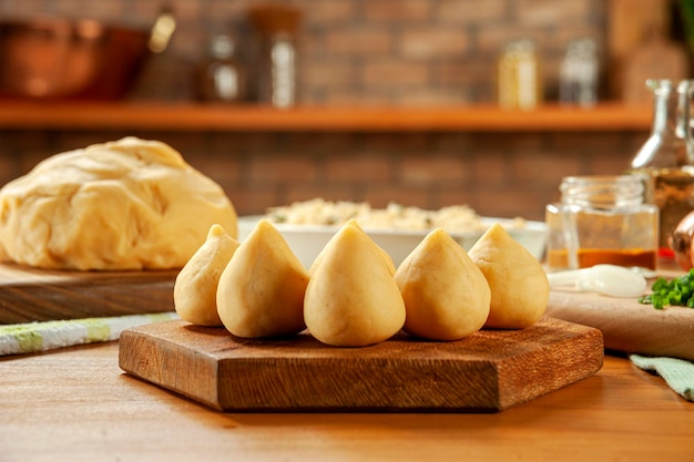 나무 테이블과 벽돌 주방 배경에 있는 브라질 치켄 크로켓 coxinha de frango