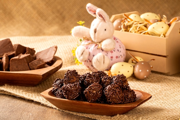 Brazilian chocolate truffle bonbon brigadeiro on wooden table with strawberry and easter background.