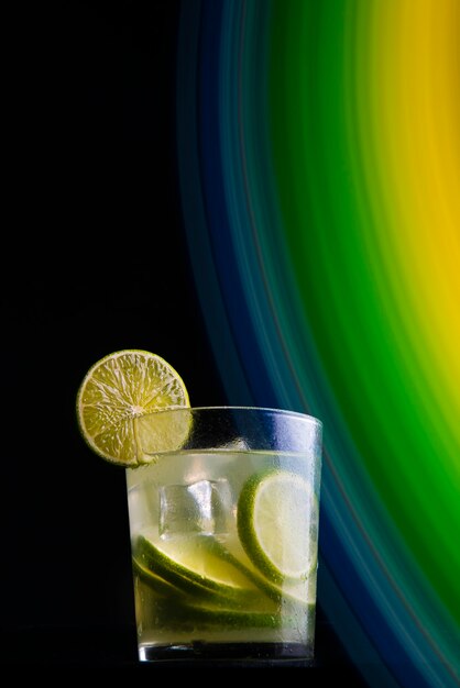 Brazilian cocktail called Caipirinha. With lemon, ice and cachaÃ§a on a dark background with colored lights. Copy space