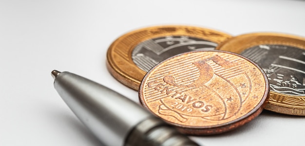 Monete brasiliane su carta bianca in macrofotografia per il concetto di finanza e risparmio