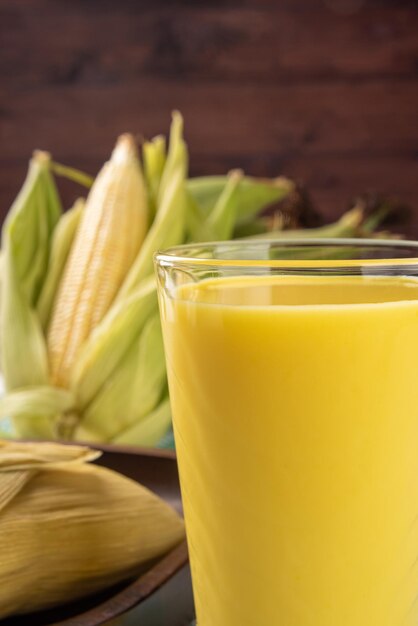 Brazilian corn snack pamonha corn and corn juice arranged on a table with green and white tablecloth dark background selective focus