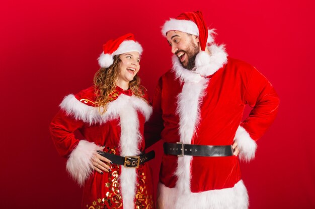 Brazilian couple dressed in christmas clothes santa claus smiling at camera