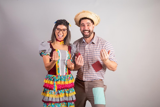 Brazilian couple dressed in festa junina clothes feast of Sao Joao inviting with hands come here