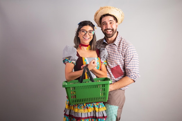 Brazilian couple dressed in festa junina clothes feast of Sao Joao with shopping basket from super market