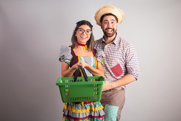 Brazilian couple dressed in festa junina clothes feast of Sao Joao with shopping basket from super market