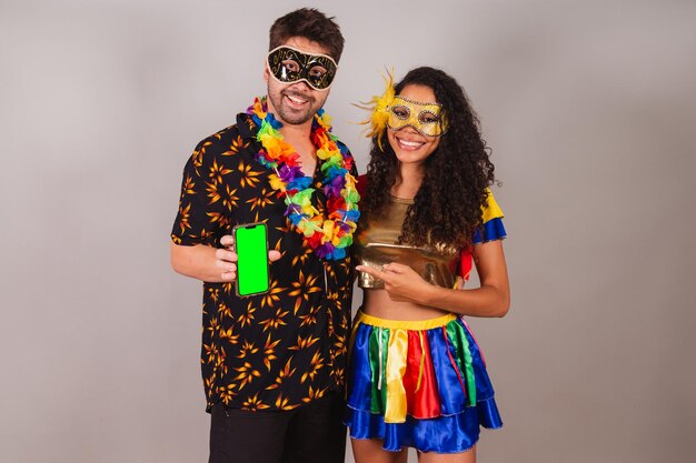 Brazilian couple with carnival clothes of holding smartphone mobile