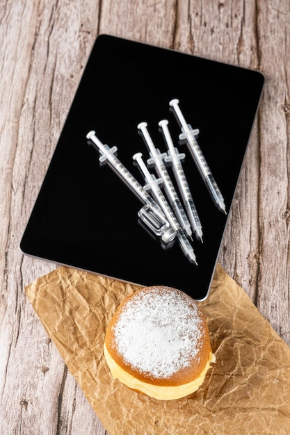 Brazilian cream donuts next by several syringes and ampoules with insulin on the tablettop viewvertical