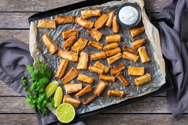 Brazilian cuisine food, latin snack. Fried yucca, yuca, cassava, manioca sticks with cilantro sauce. Top view flat lay background