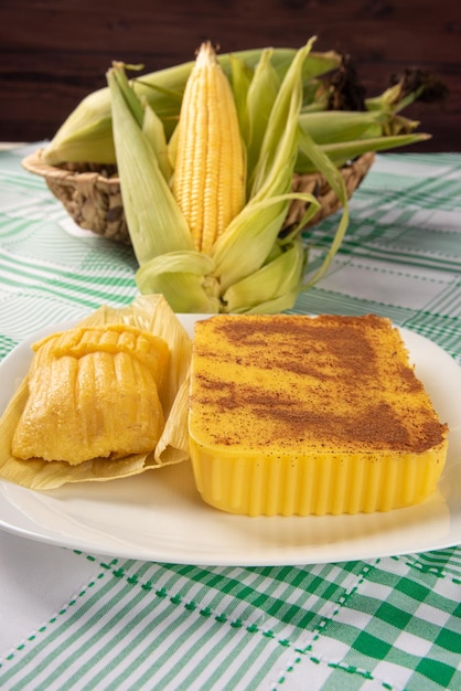 Brazilian Cural candy corn and pamonha corn on the cob arranged on a table with a green and white tablecloth dark background selective focus