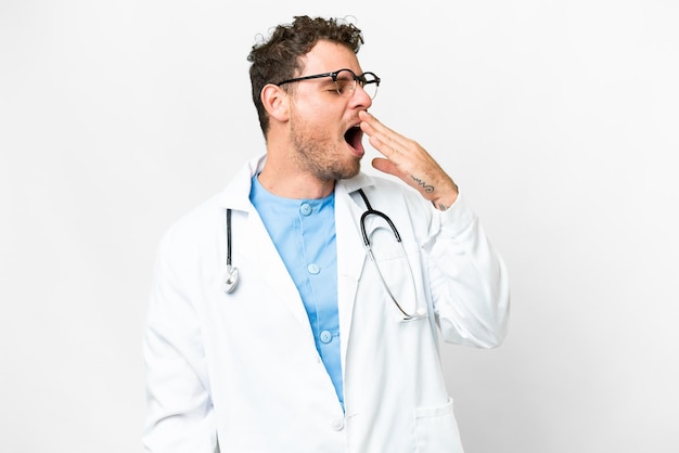 Brazilian doctor man over isolated white background yawning and covering wide open mouth with hand