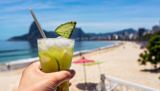 Brazilian drink caipirinha. Hand holding a caipirinha drink with blurred foliage in the background.