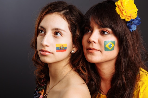 Brazilian and Ecuadorian ladies with body art on their faces looking forward Colorful painting Selective focus