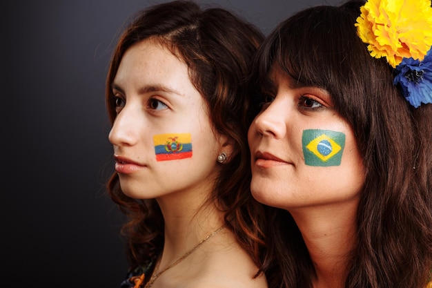 Brazilian and Ecuadorian ladies with body art on their faces looking forward Colorful painting Selective focus