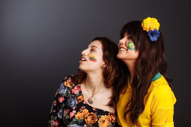 Бразильские и эквадорские дамы с боди-артом на лицах смотрят вперед и удивлены Красочная живопись Выборочный фокус