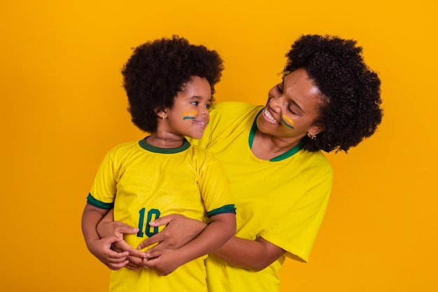 Brazilian family cheering together fans celebrating over yellow background faces painted and cheering with the yellow tshirt