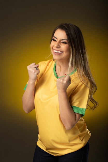 Fan brasiliana fan brasiliana che festeggia in una partita di calcio o di calcio su sfondo giallo colori del brasile