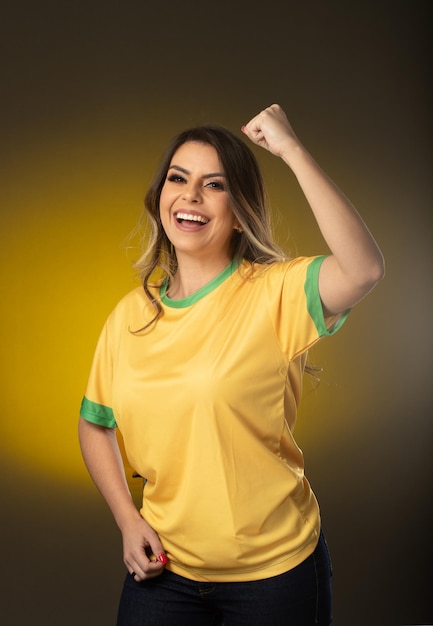 Brazilian fan Brazilian woman fan celebrating in soccer or soccer match on yellow background Brazil colors