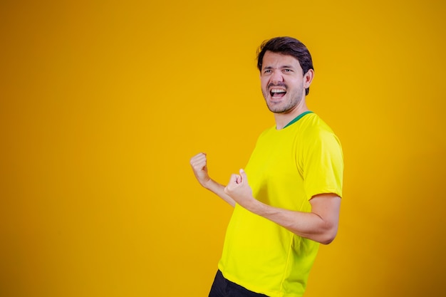 Brazilian fan celebrating on yellow background. yes!