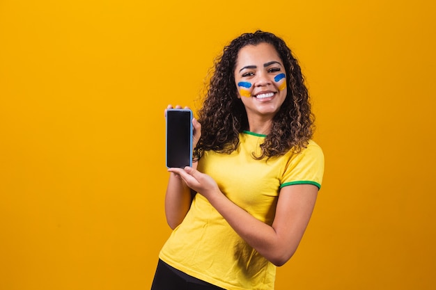 Brazilian fan holding a smartphone  with copy space