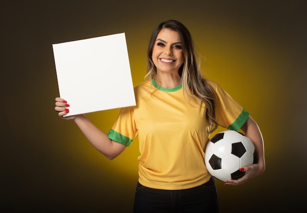 Brazilian fan Holding White Blank Card woman fan celebrating in soccer or soccer match on yellow background Brazil colors