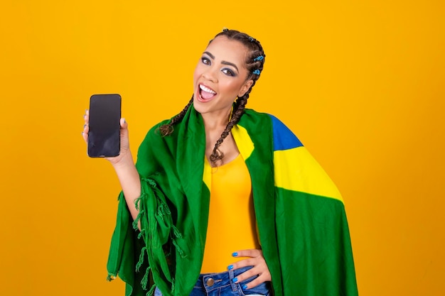 Brazilian fan portrait brazilian fan showing her cellphone dressed as soccer fan or soccer game on yellow background Brazil colors World Cup