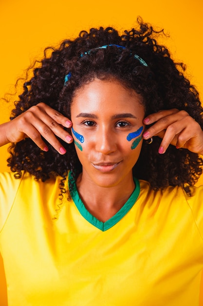 Brazilian fan. using paint as makeup, Brazilian fan celebrating football or soccer game. Colors of Brazil.