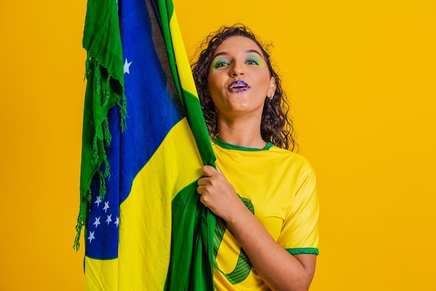 Brazilian fan wearing brazilian flag in a portrait brazilian\
fan celebrating football or soccer game on yellow background colors\
of brazilworld cup