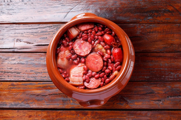 brazilian feijoada in ceramic bowl isolated on rustic wooden background Copy space