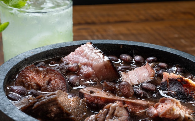 Foto feijoada brasiliana, cibo tipico servito con carne secca, salsicce, maiale e fagioli neri e per accompagnare una tradizionale caipirinha