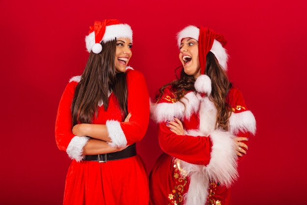 Brazilian female friends dressed in Christmas clothes Santa Claus with arms crossed