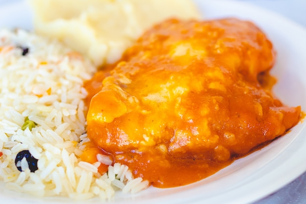 Cibo brasiliano alla parmigiana di pollo con riso greco e purè di patate su un piatto bianco